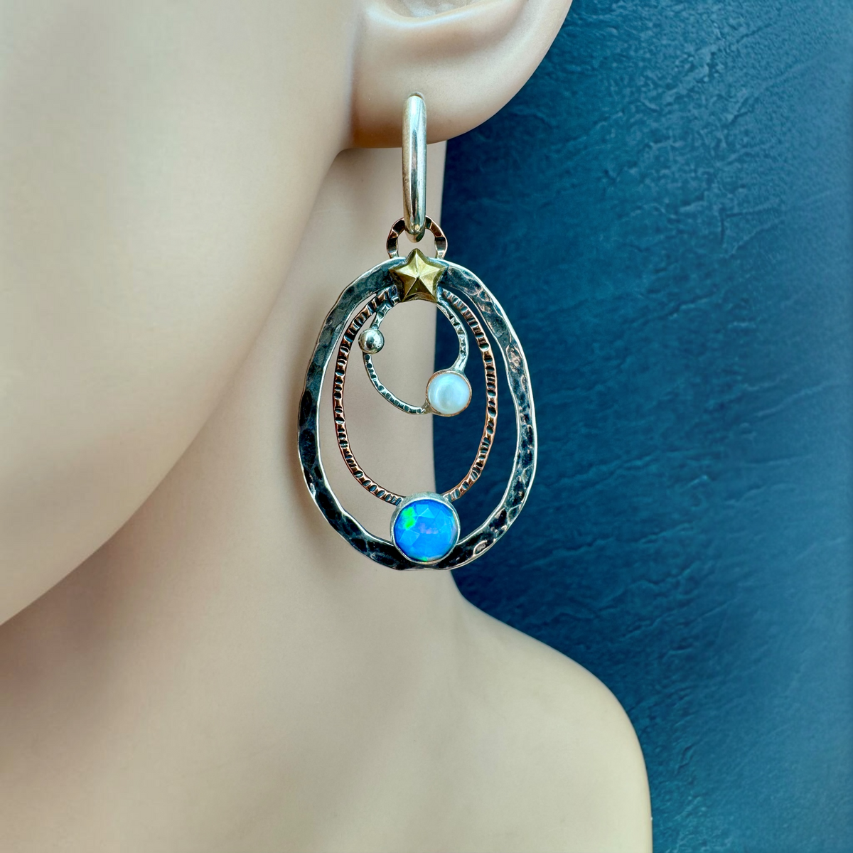 Opal and Pearl Orbit Earring shown on the ear, nested silver and copper orbits with rosecut Ethiopian opal