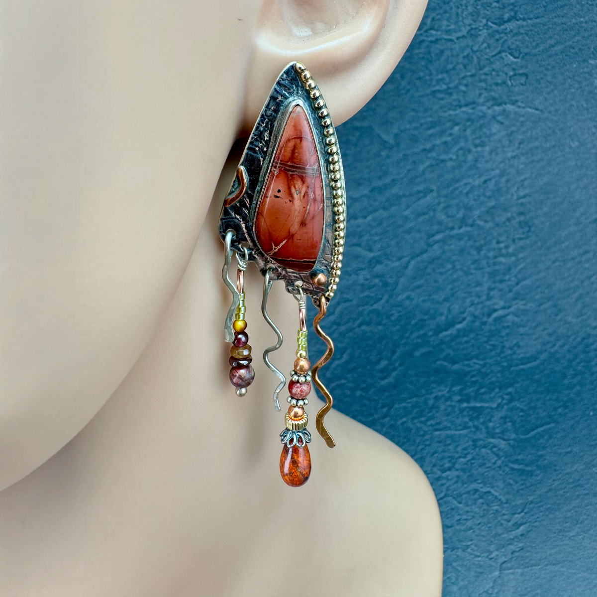 Red Jasper Shield Earring shown on the ear, textured sterling silver shield with 14k gold beading and gemstone dangles